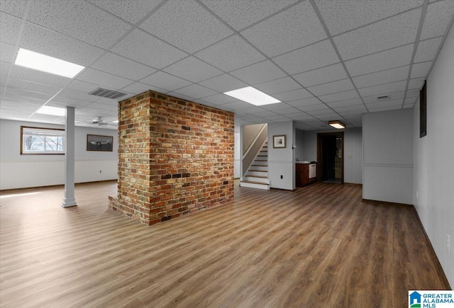 below grade area featuring stairs, a paneled ceiling, wood finished floors, and visible vents