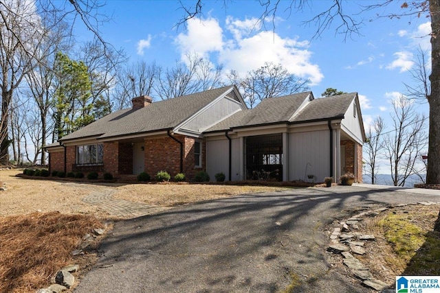 exterior space with a chimney, aphalt driveway, and brick siding