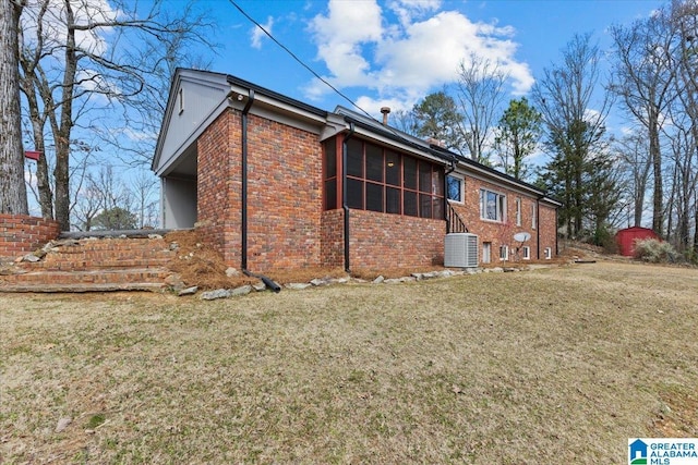 exterior space with a sunroom, central AC, a lawn, and brick siding