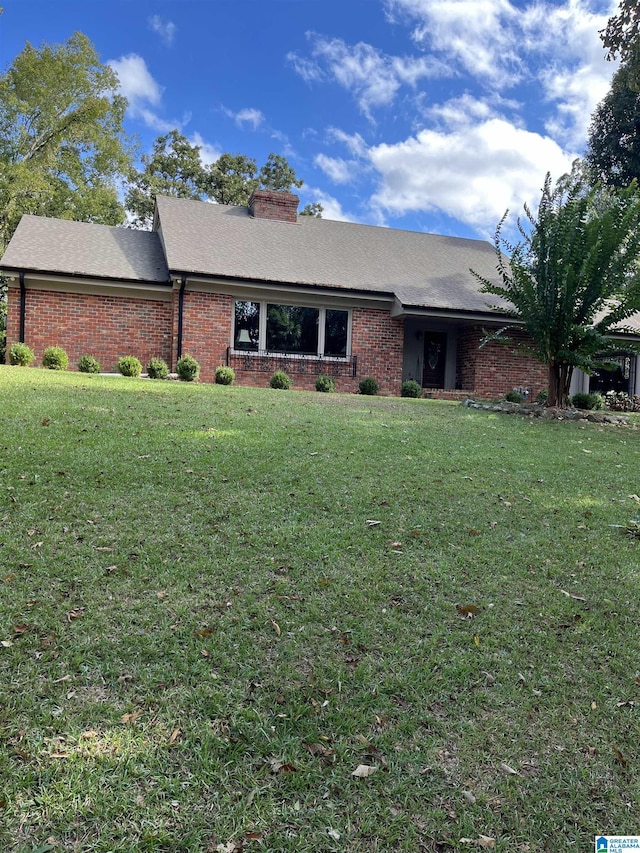 ranch-style house featuring a front lawn, a chimney, and brick siding