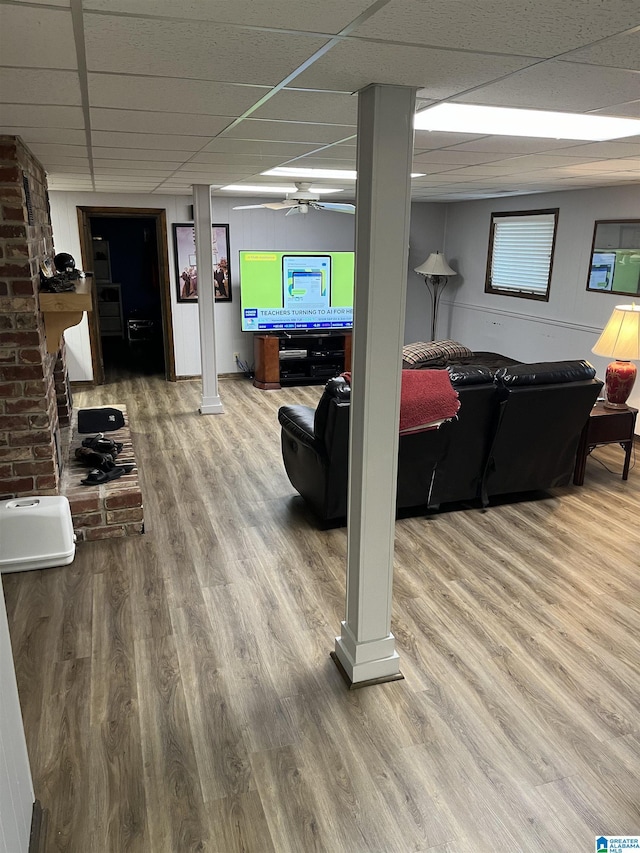 interior space with decorative columns, a drop ceiling, and wood finished floors