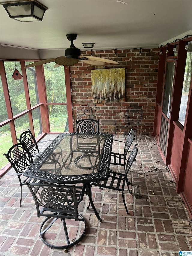 interior space with brick floor, brick wall, a ceiling fan, and a sunroom