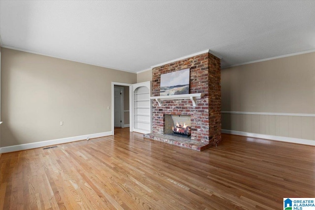 unfurnished living room with baseboards, wood finished floors, crown molding, a textured ceiling, and a fireplace