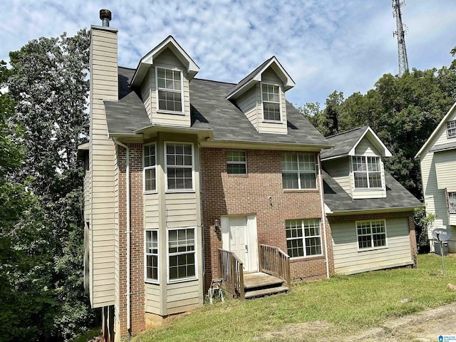 back of property with a chimney, a lawn, and brick siding