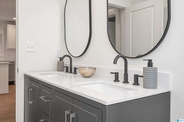 full bath featuring double vanity, a sink, and wood finished floors