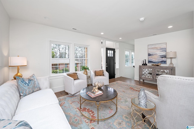 living area with recessed lighting, visible vents, baseboards, and wood finished floors