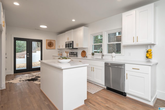 kitchen with wood finished floors, light countertops, stainless steel appliances, french doors, and a sink