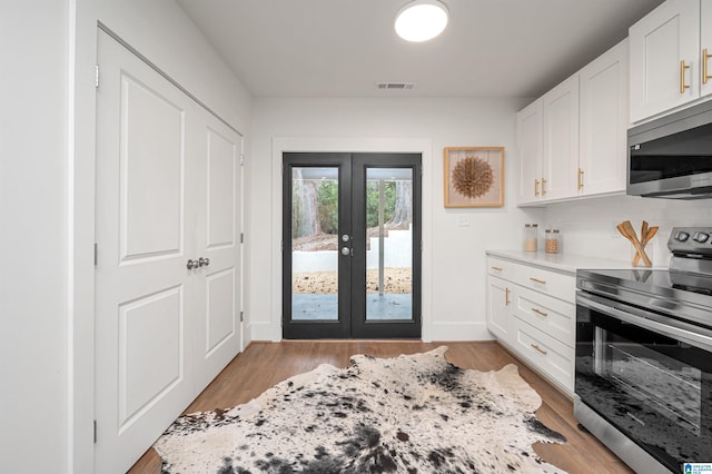 kitchen featuring french doors, visible vents, light wood-style flooring, backsplash, and appliances with stainless steel finishes