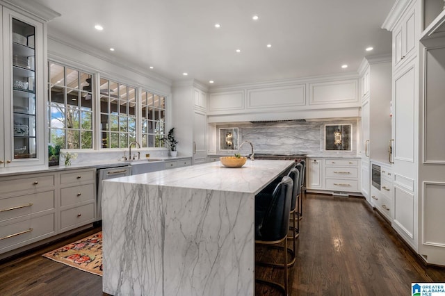 kitchen with light stone countertops, dark wood-style flooring, decorative backsplash, dishwasher, and a center island with sink