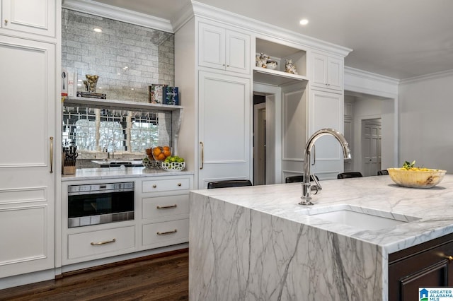 kitchen featuring a sink, white cabinetry, stainless steel oven, open shelves, and crown molding