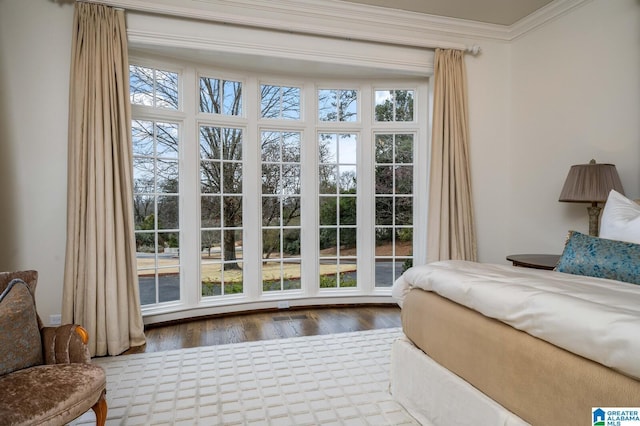 bedroom with ornamental molding and wood finished floors