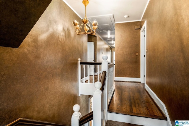 hallway with attic access, baseboards, wood finished floors, crown molding, and an upstairs landing