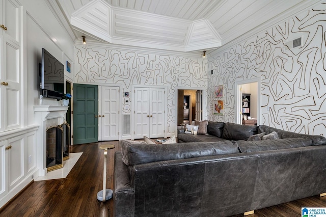 living area featuring ornamental molding, dark wood-style flooring, a fireplace with flush hearth, and wallpapered walls