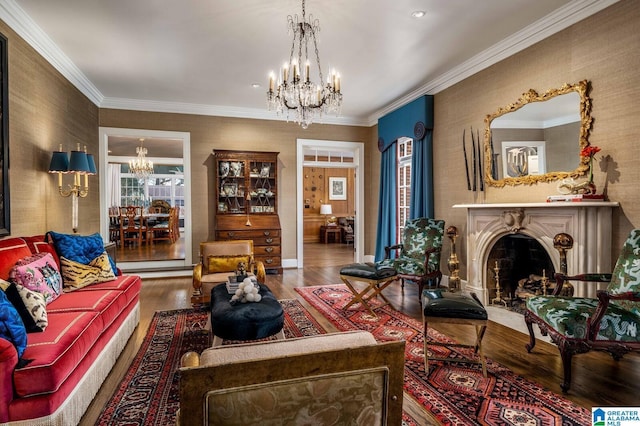 living room with a chandelier, ornamental molding, a fireplace, and wood finished floors