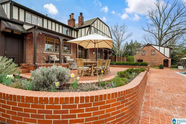 exterior space with brick siding, a chimney, and a patio area