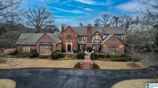 tudor home with brick siding and a chimney