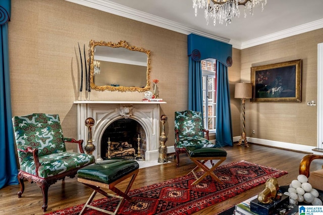 living area with crown molding, a fireplace with flush hearth, wood finished floors, baseboards, and wallpapered walls