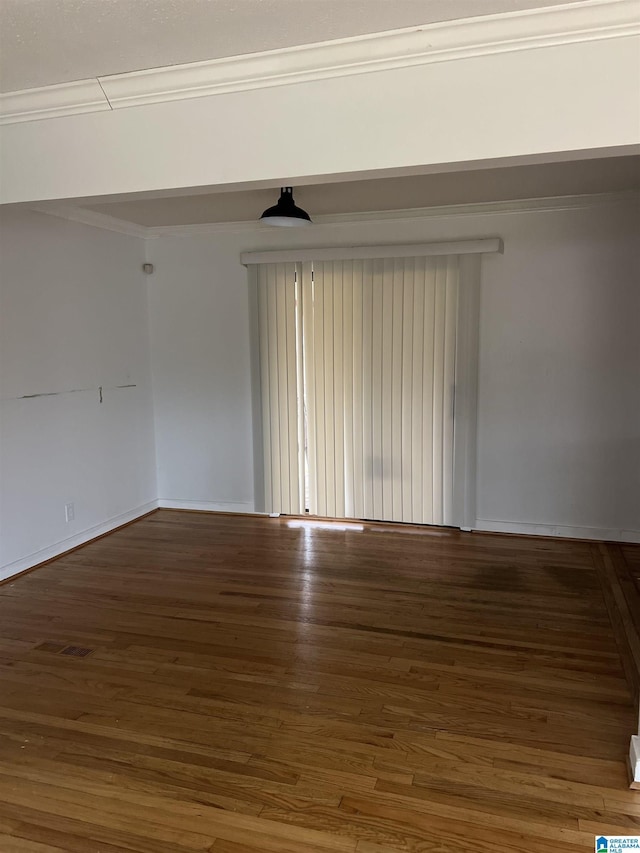 unfurnished room with ornamental molding, baseboards, and wood finished floors