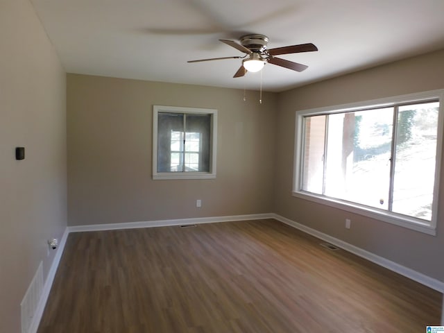 spare room with baseboards, visible vents, ceiling fan, and wood finished floors