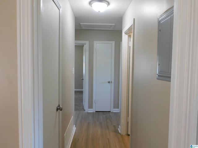 hall with attic access, visible vents, baseboards, and wood finished floors