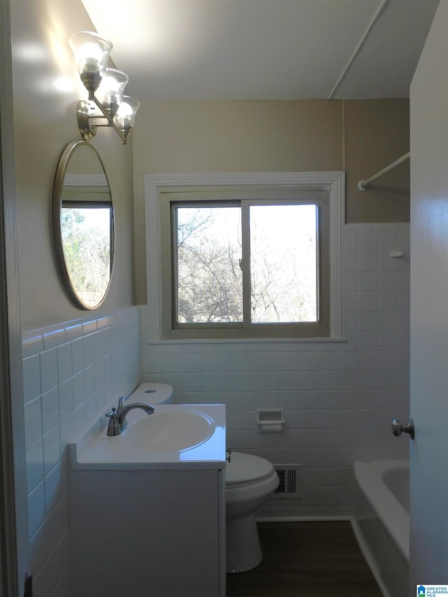 bathroom with toilet, a wealth of natural light, vanity, and visible vents