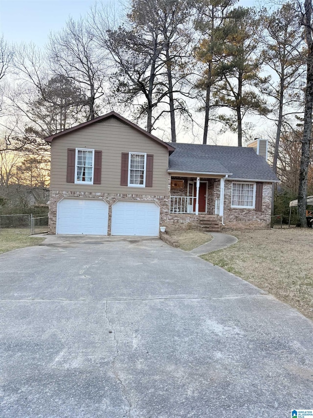 tri-level home with driveway, an attached garage, a chimney, and a shingled roof