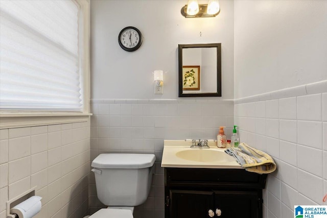 bathroom featuring tile walls, wainscoting, vanity, and toilet