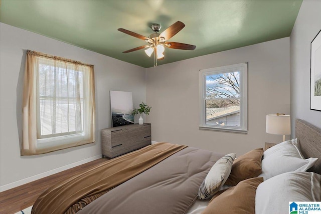 bedroom with a ceiling fan, baseboards, and wood finished floors