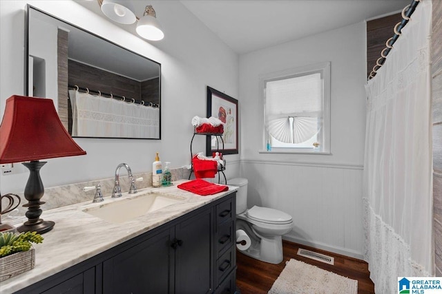 bathroom featuring visible vents, toilet, a wainscoted wall, wood finished floors, and vanity