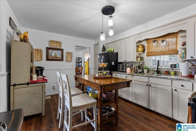 kitchen with decorative backsplash, wainscoting, dark wood-style floors, freestanding refrigerator, and a sink