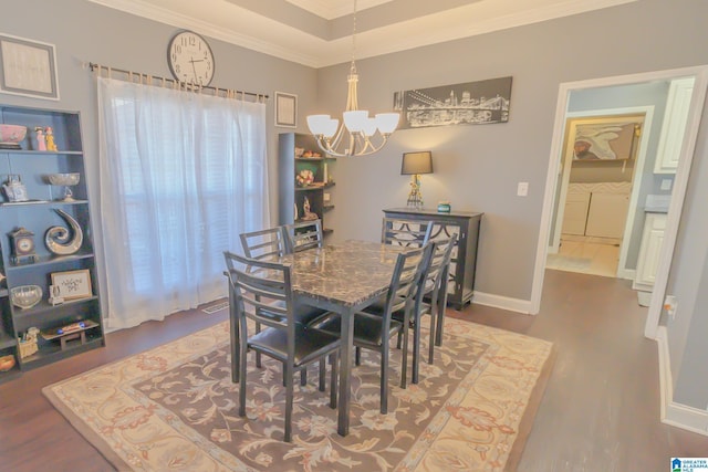 dining space featuring ornamental molding, a notable chandelier, washing machine and clothes dryer, and wood finished floors