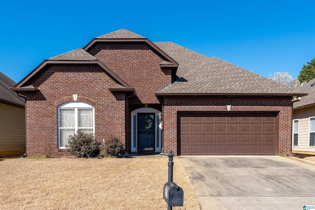 view of front facade with a front yard, brick siding, an attached garage, and a shingled roof