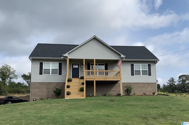 view of front facade featuring brick siding, covered porch, a front lawn, and roof with shingles