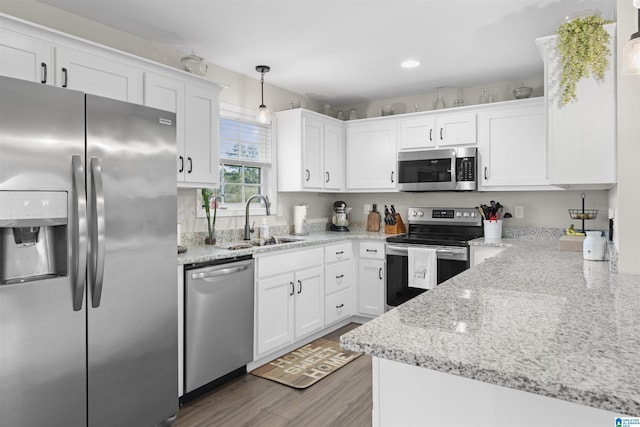 kitchen with white cabinetry, wood finished floors, appliances with stainless steel finishes, and a sink