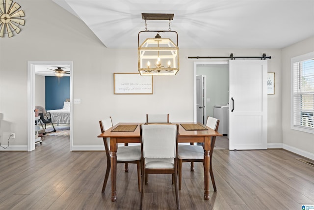 dining room featuring a barn door, wood finished floors, baseboards, and visible vents