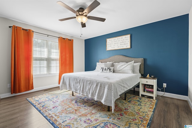 bedroom with visible vents, wood finished floors, and baseboards