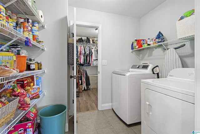 clothes washing area with light tile patterned floors, laundry area, washing machine and dryer, and baseboards