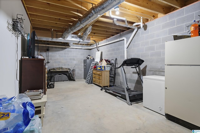 unfinished basement featuring refrigerator and freestanding refrigerator