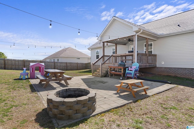 view of patio featuring a wooden deck, a fenced backyard, a ceiling fan, and an outdoor fire pit