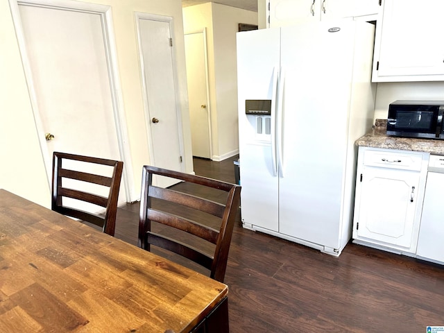 kitchen featuring light stone counters, white appliances, dark wood-style flooring, and white cabinetry