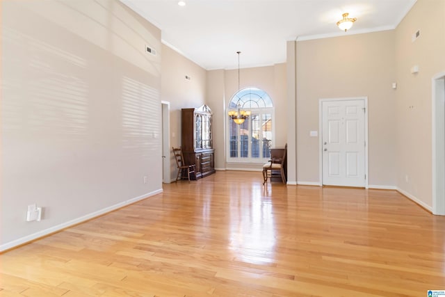 interior space with a chandelier, ornamental molding, baseboards, and light wood-style floors