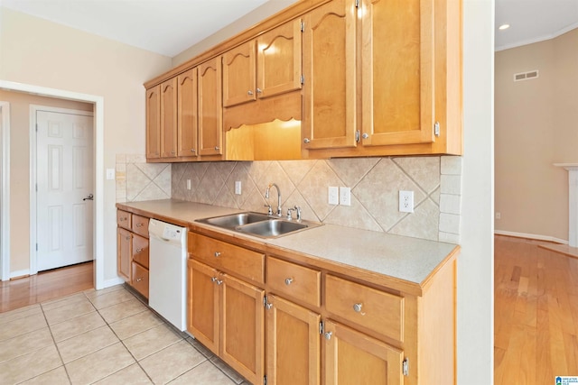 kitchen featuring light countertops, visible vents, backsplash, white dishwasher, and a sink