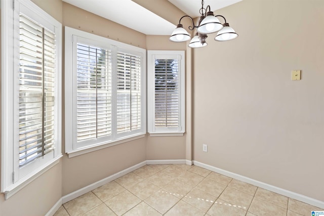 unfurnished dining area featuring a chandelier, light tile patterned floors, and baseboards