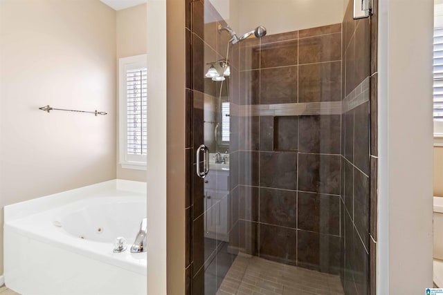 bathroom featuring a jetted tub and a shower stall