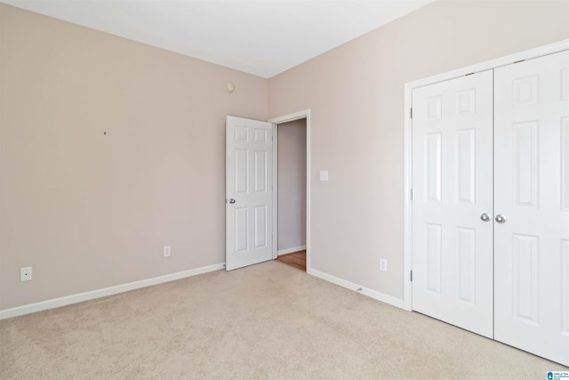 unfurnished bedroom featuring light carpet, a closet, and baseboards