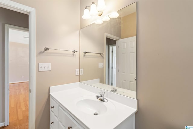 bathroom featuring an inviting chandelier, wood finished floors, and vanity