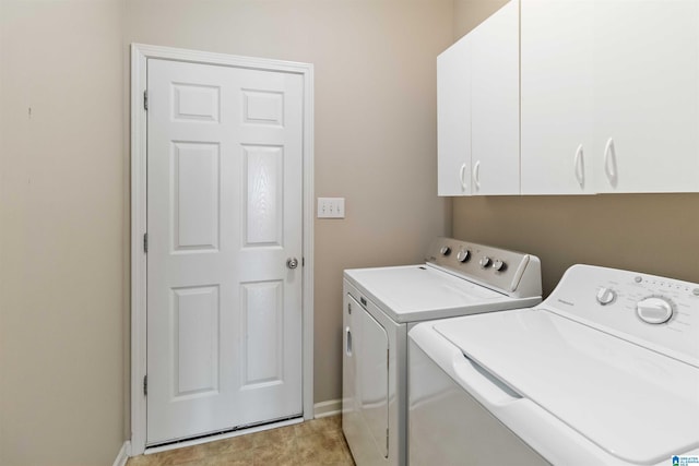 washroom featuring washing machine and dryer, cabinet space, and baseboards