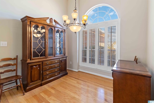 dining space featuring baseboards, light wood finished floors, and an inviting chandelier