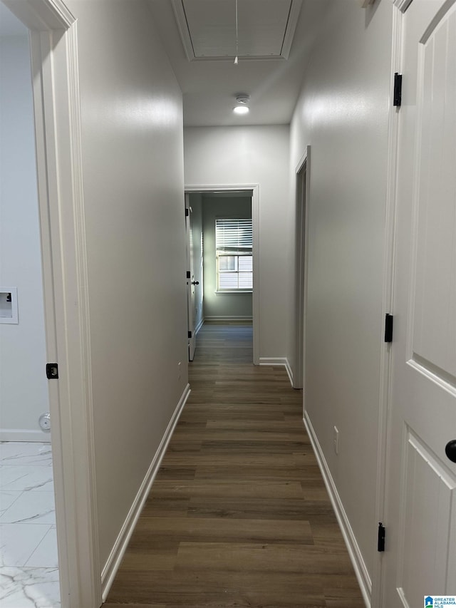 hall with dark wood-style flooring, attic access, and baseboards