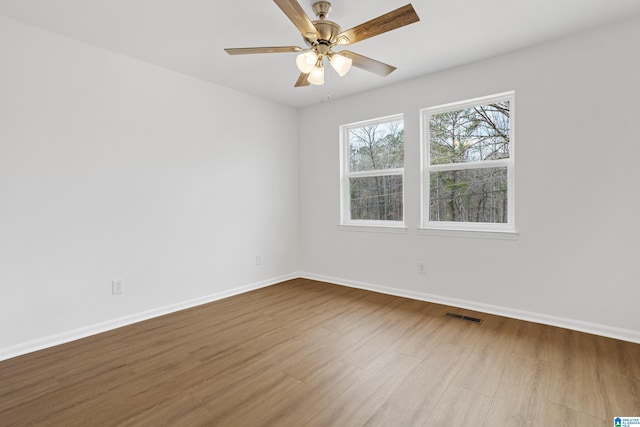 spare room with baseboards, visible vents, and wood finished floors